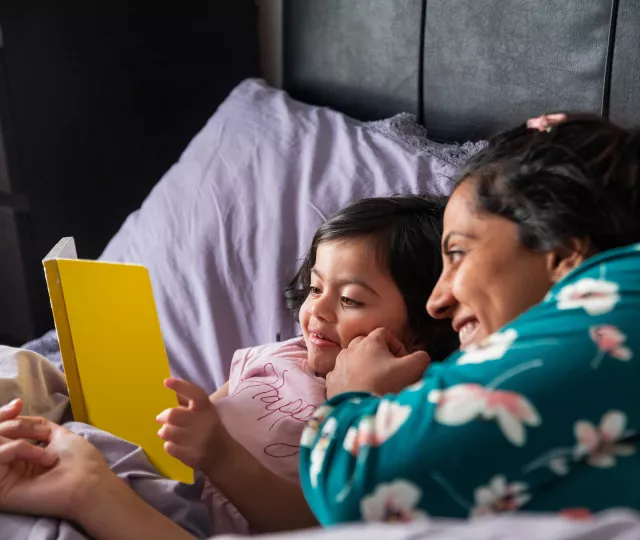 Mother and child holding reading in bed