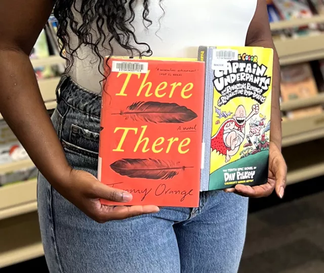 Taffy Maposa holding two books at Beacock Branch Library.