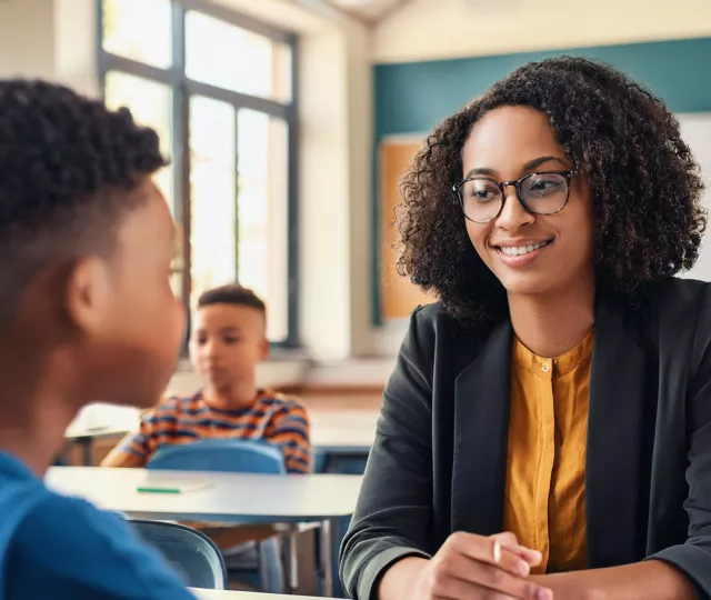 A Teacher talking to a tween Student in a class room