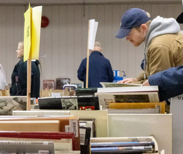 Patrons sifting through boxes of books at a sale.