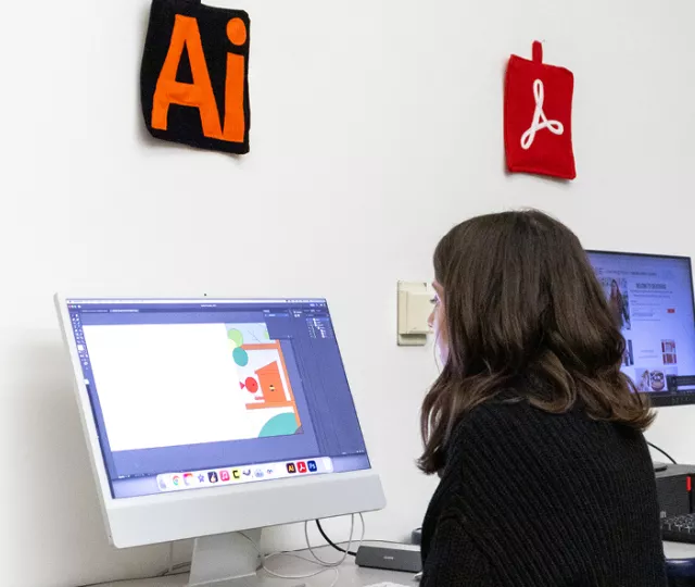 A person using illustrator on a mac computer at the design station