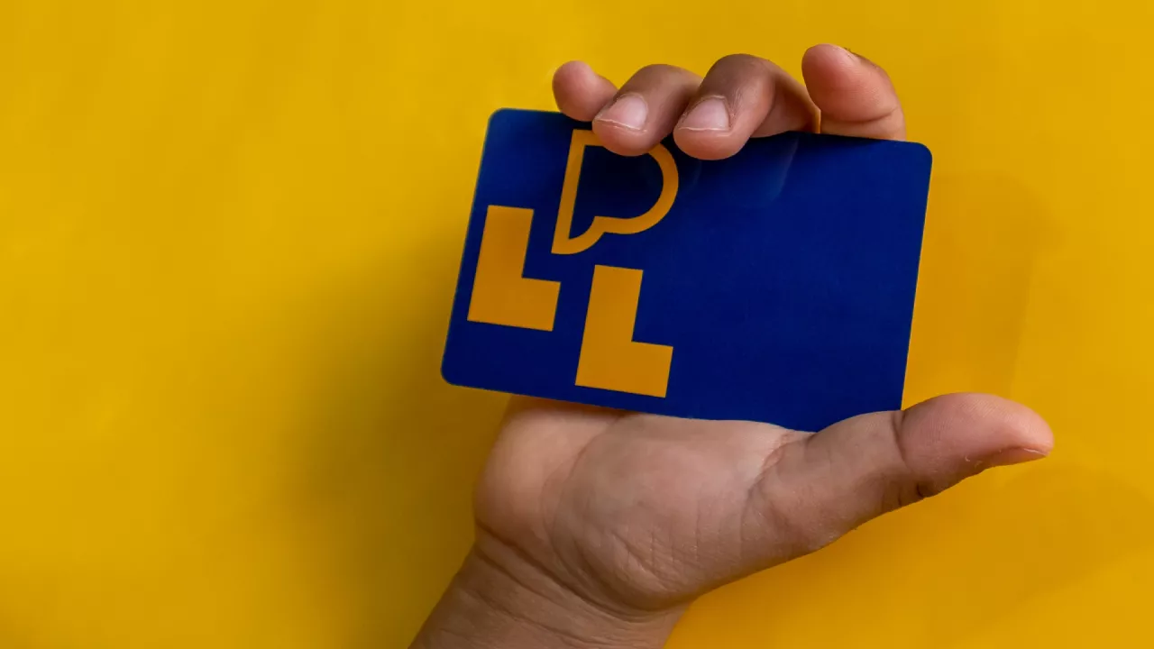 Youth holding navy library card against a yellow background