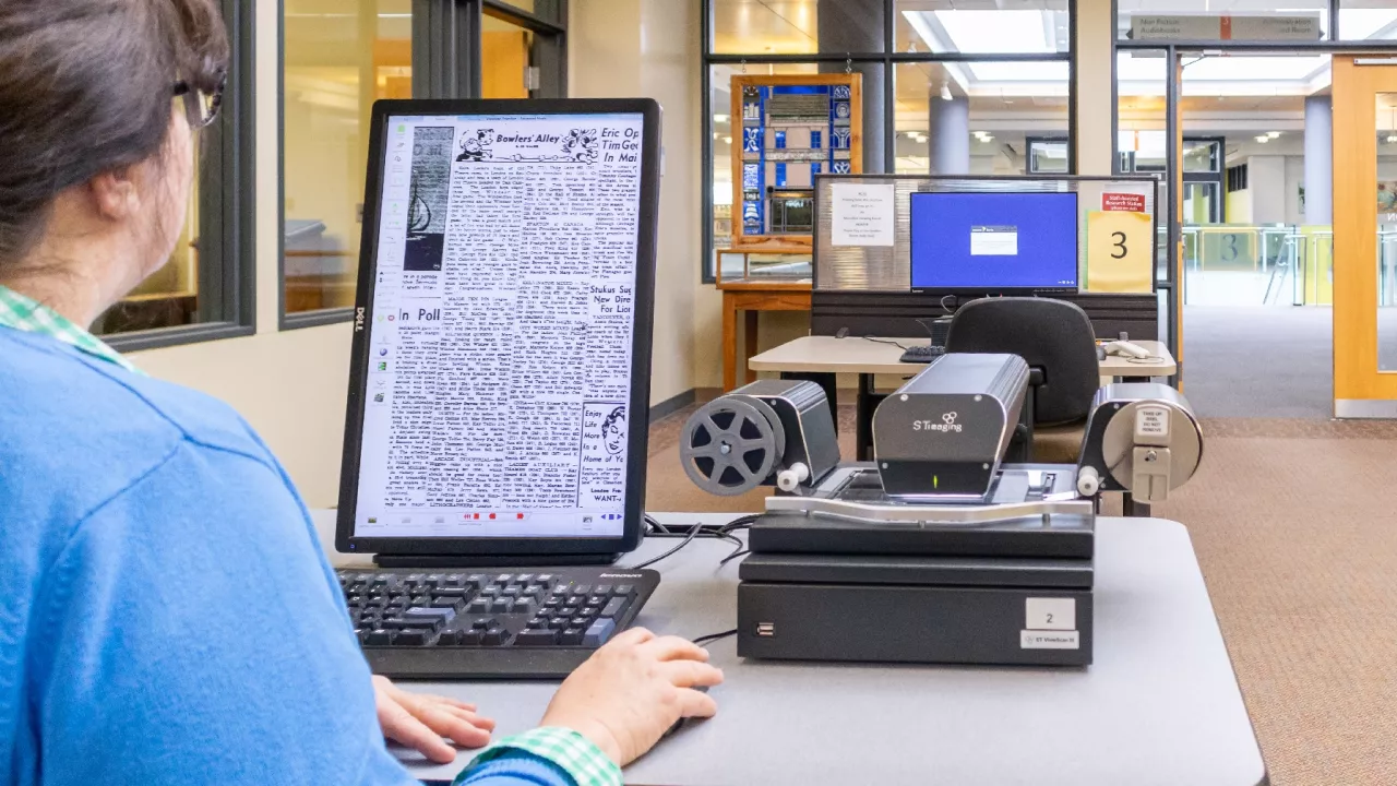 Photo of a woman using the microfilm reader in the London Room.