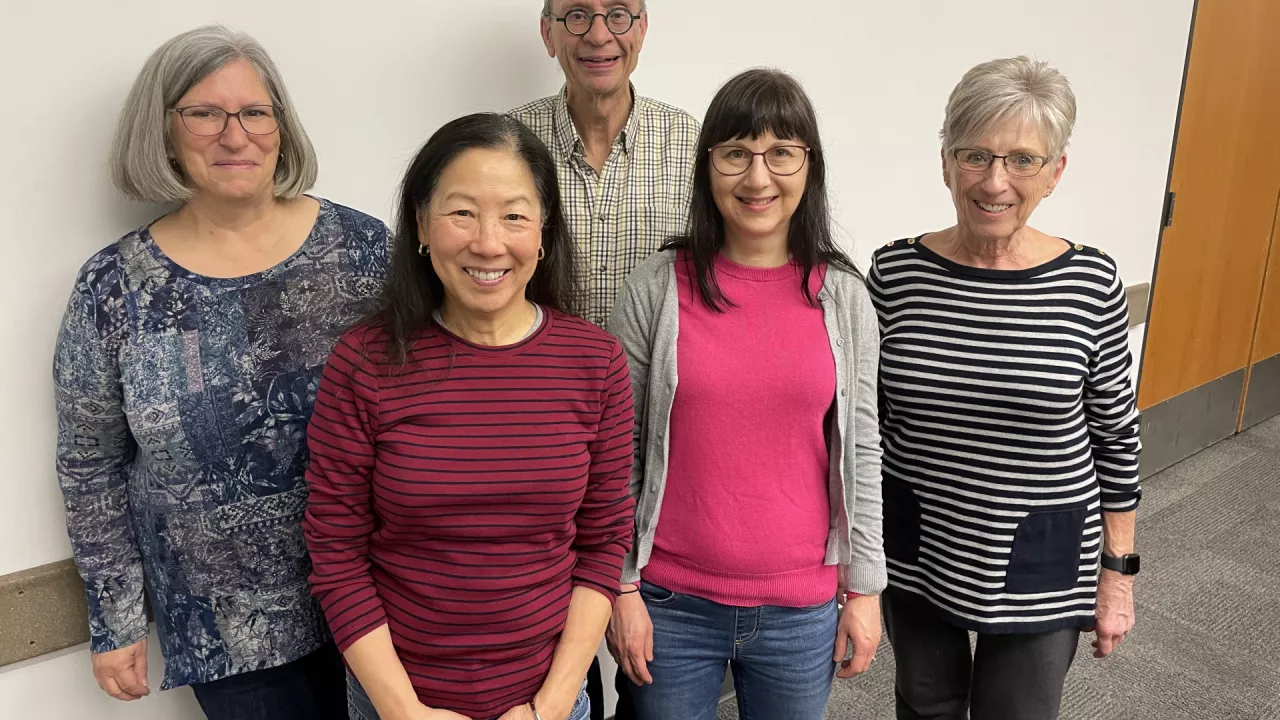 Photo of five older adults standing and smiling.