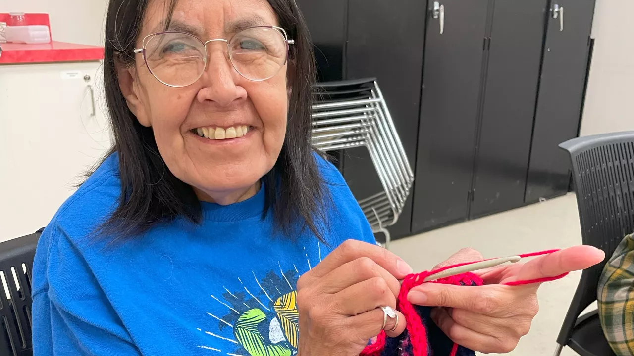 person knitting blanked in kitting club