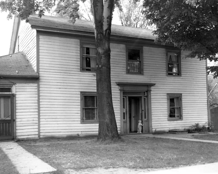 Black and white photograph of a The White Ox Inn with a child standing in the doorway