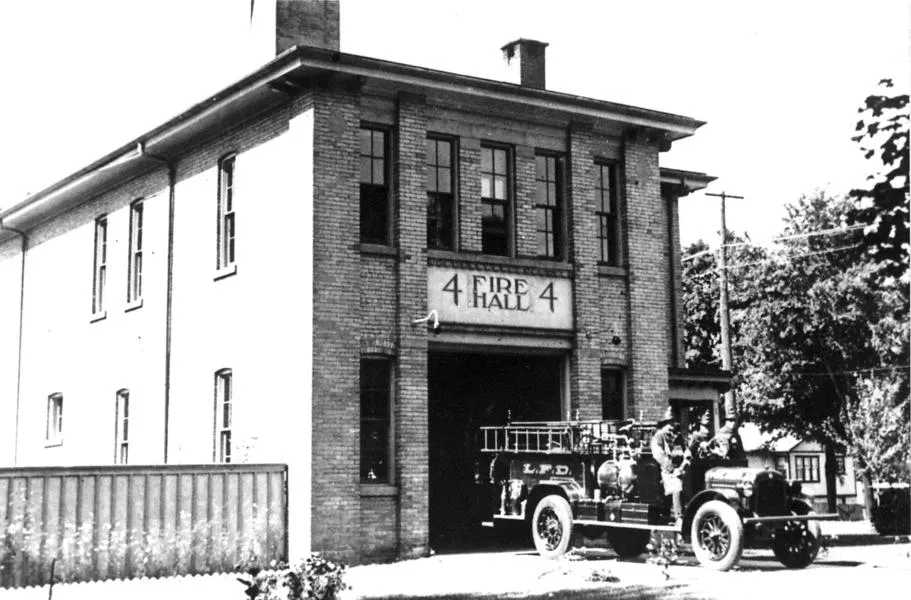 Black and white photograph of fire station, fire engine and fire fighters. Looking northwest