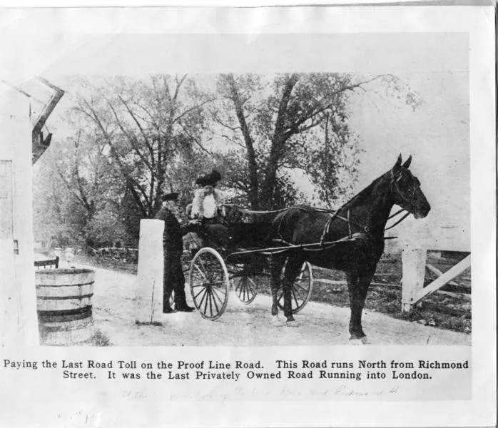 A black and white photograph showing an elegantly dressed lady seated in a single horse drawn buggy, paying the last toll