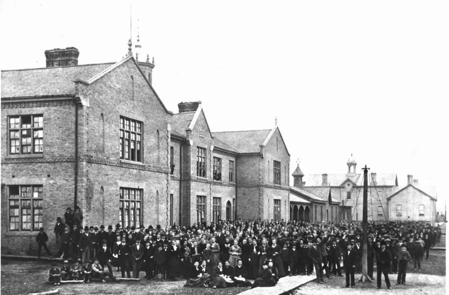 Black and white photograph of a building with a large group of people in front