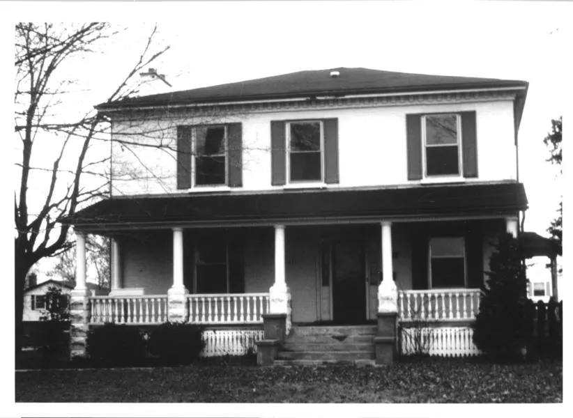 Black and white photograph of a two story house with a porch