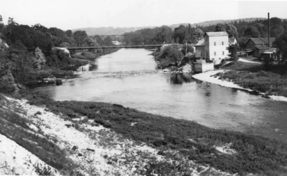   Black and white photo of the Thames River, dam and building in the background