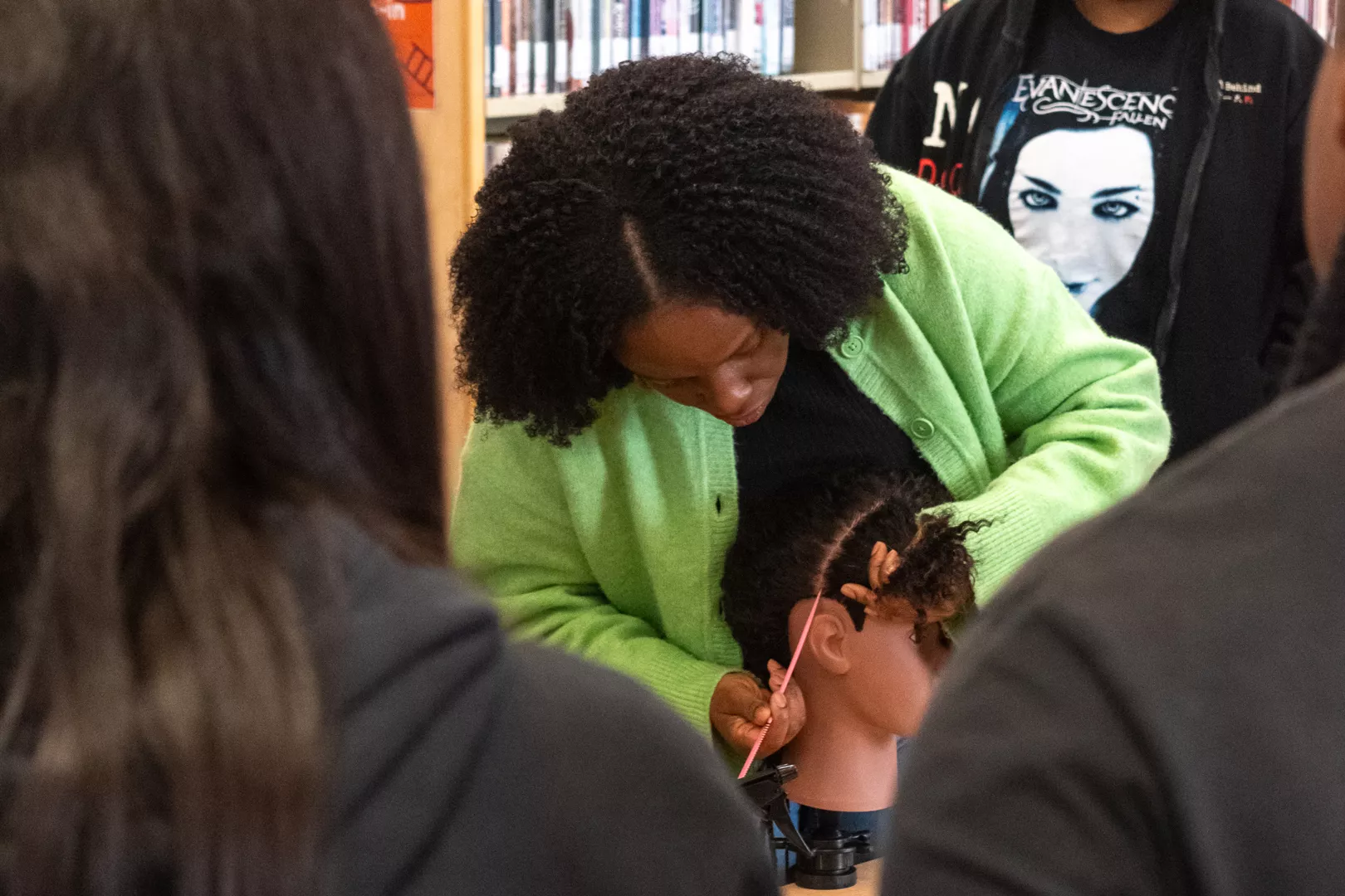 Taffy Maposa showing teens how to section hair on a mannequin,